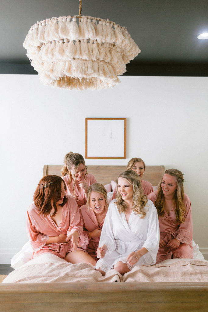 Bride with bridesmaids wearing silk BHLDN robes gettig ready morning of